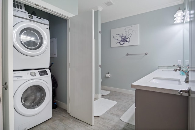 laundry area featuring stacked washing maching and dryer, wood tiled floor, visible vents, and a sink