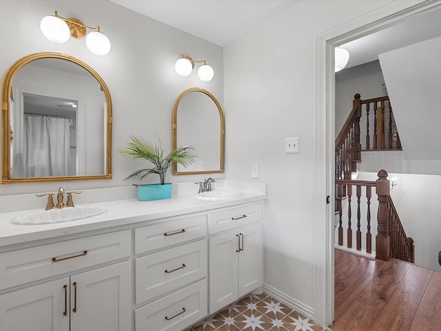 bathroom with double vanity, baseboards, and a sink