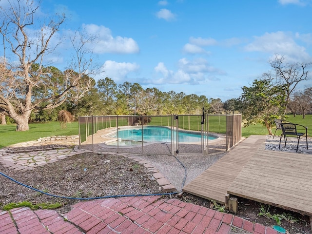 view of swimming pool featuring a lawn, a wooden deck, and a fenced in pool