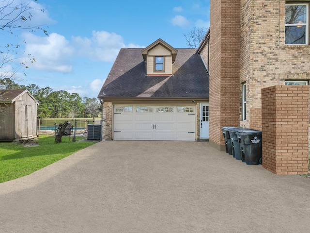 view of side of property featuring roof with shingles, a chimney, a storage unit, an attached garage, and cooling unit