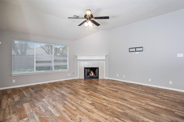 unfurnished living room featuring lofted ceiling, wood finished floors, a fireplace, and baseboards