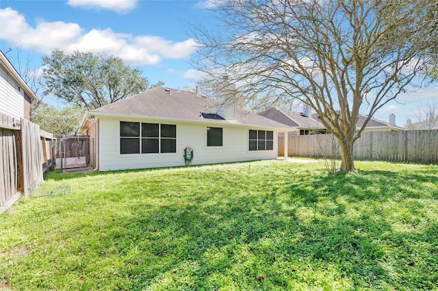 rear view of property with a yard, a fenced backyard, and a shingled roof