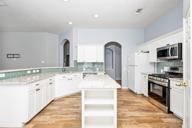 kitchen with light wood finished floors, visible vents, appliances with stainless steel finishes, a peninsula, and open shelves