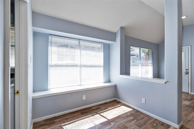 spare room with vaulted ceiling, baseboards, and wood finished floors