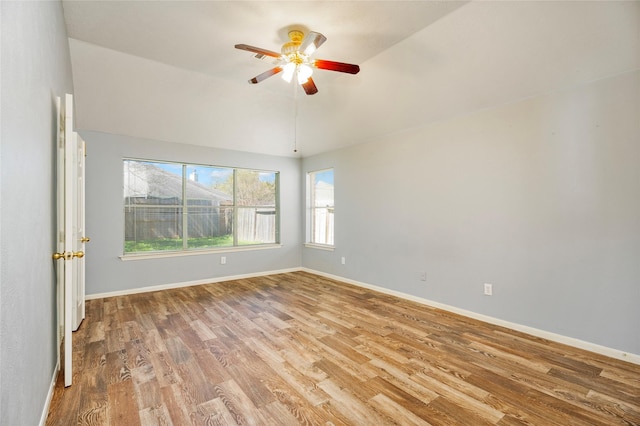 unfurnished room featuring baseboards, lofted ceiling, wood finished floors, and a ceiling fan