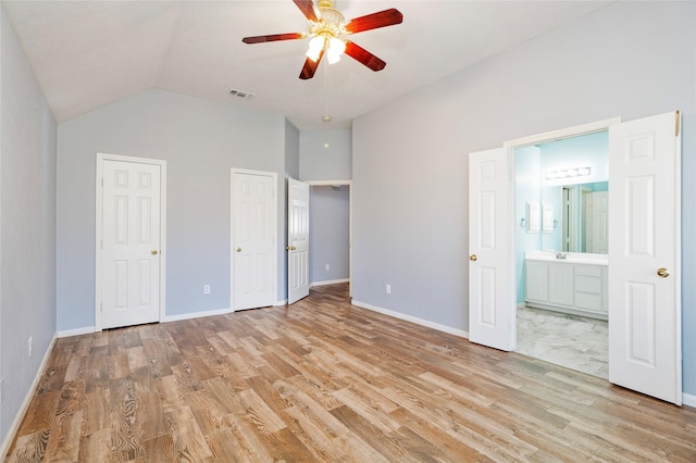 unfurnished bedroom with visible vents, multiple closets, lofted ceiling, and light wood finished floors