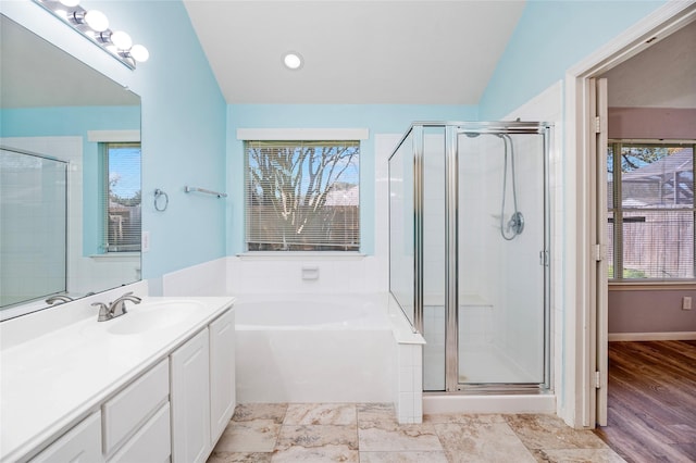 bathroom featuring vanity, a bath, a shower stall, and vaulted ceiling