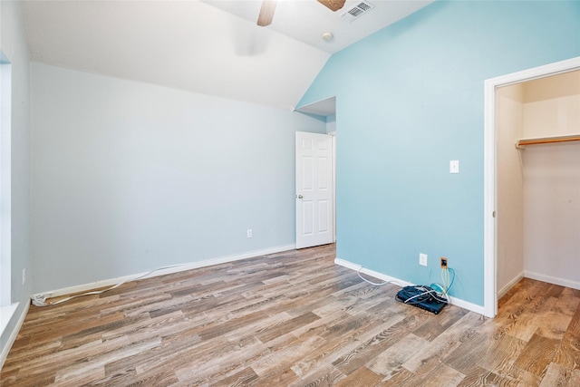 unfurnished bedroom with vaulted ceiling, visible vents, baseboards, and wood finished floors