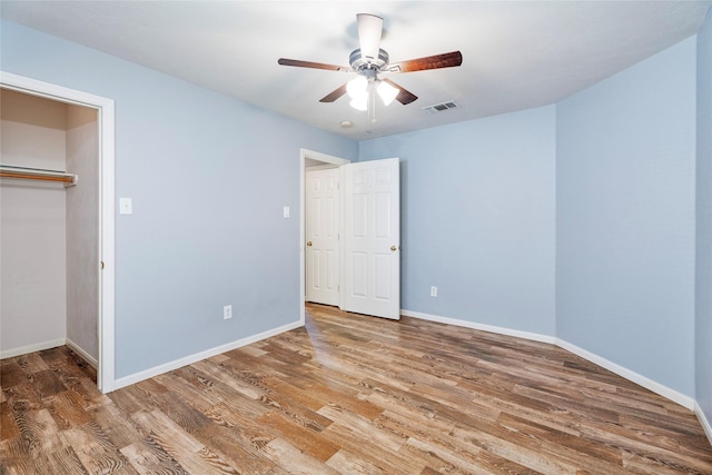 unfurnished bedroom featuring visible vents, baseboards, wood finished floors, and a ceiling fan