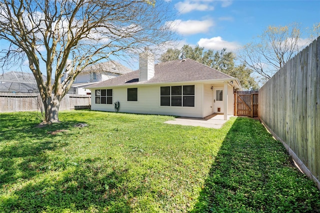 rear view of house with a patio, a fenced backyard, a chimney, a shingled roof, and a lawn