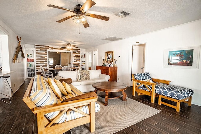 living room with a ceiling fan, visible vents, a textured ceiling, and wood finished floors