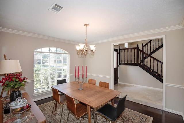 dining space with a notable chandelier, wood finished floors, visible vents, stairs, and ornamental molding