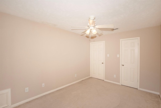 unfurnished bedroom featuring a ceiling fan, visible vents, light carpet, and baseboards