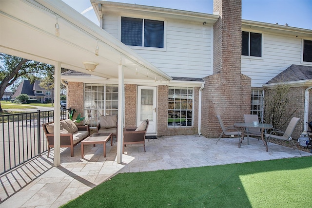 rear view of property with an outdoor hangout area, brick siding, a yard, a chimney, and a patio area