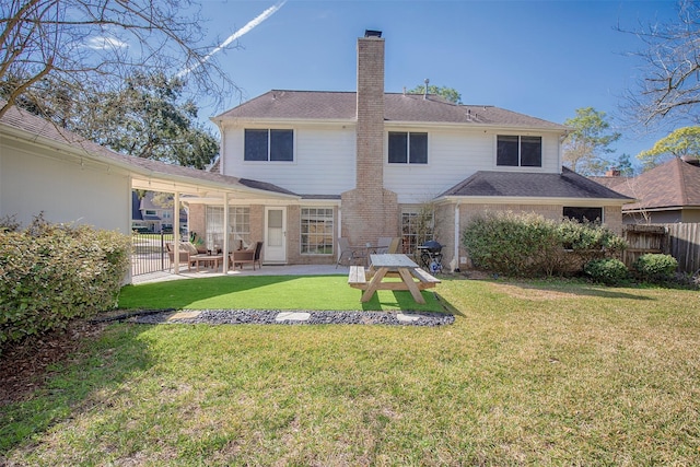 back of house featuring a lawn, a chimney, fence, a patio area, and brick siding