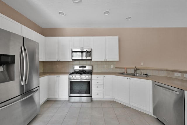 33 Stone Creek Pl, The Woodlands, TX 77382 - kitchen featuring stainless steel appliances, a sink, white cabinets, backsplash, and light tile patterned floors