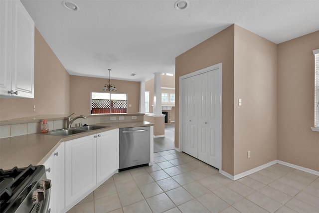 kitchen featuring light tile patterned floors, a peninsula, stainless steel appliances, white cabinetry, and a sink