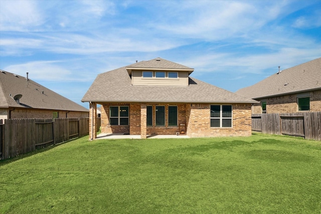 rear view of house featuring a fenced backyard, a lawn, brick siding, and roof with shingles