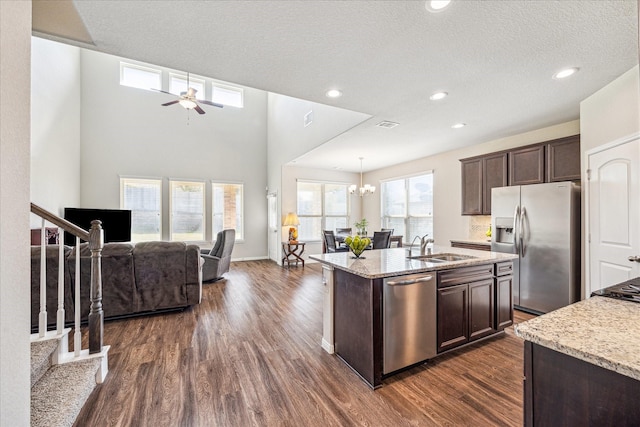 kitchen featuring dark wood-style flooring, dark brown cabinets, appliances with stainless steel finishes, ceiling fan with notable chandelier, and open floor plan