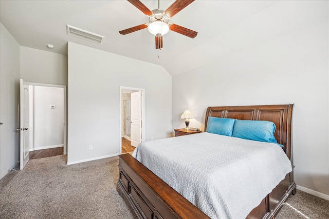 carpeted bedroom with baseboards, visible vents, lofted ceiling, ceiling fan, and ensuite bathroom