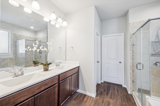 full bathroom with double vanity, a stall shower, wood finished floors, and a sink