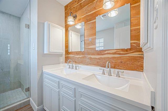 bathroom featuring double vanity, a shower stall, visible vents, and a sink