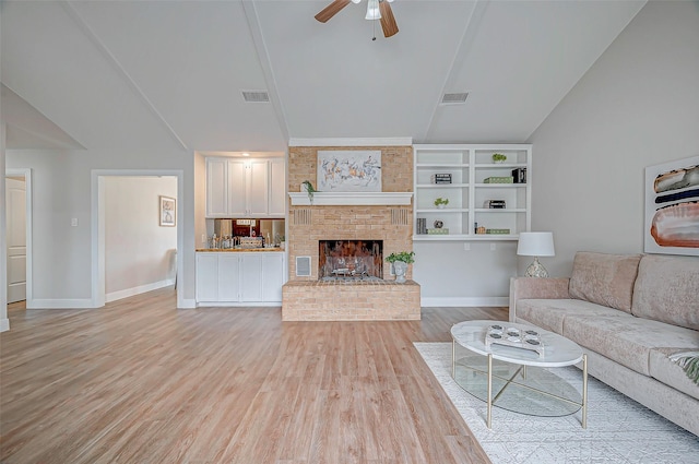 unfurnished living room with lofted ceiling, a fireplace, visible vents, and light wood-style floors