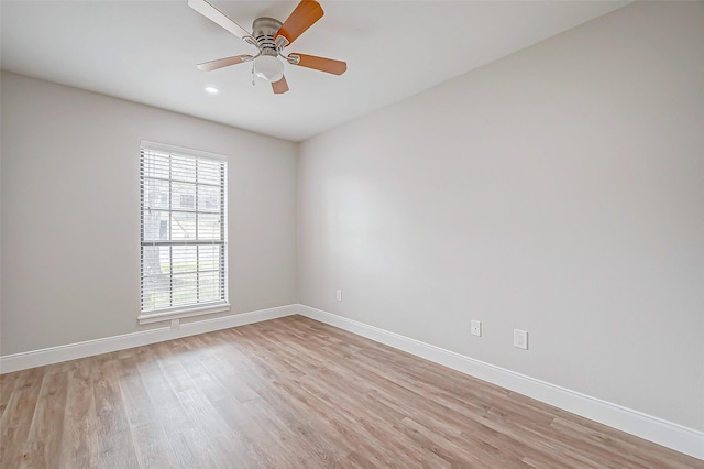 spare room featuring light wood-style floors, baseboards, and a ceiling fan