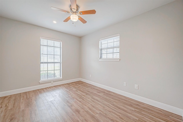 empty room featuring light wood-type flooring, plenty of natural light, a ceiling fan, and baseboards