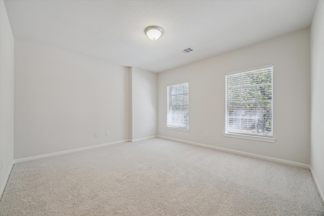 carpeted empty room with visible vents and baseboards