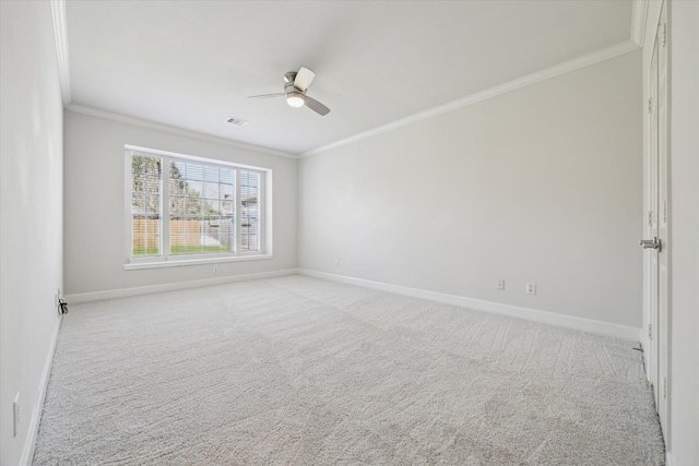 empty room with a ceiling fan, light colored carpet, crown molding, and baseboards