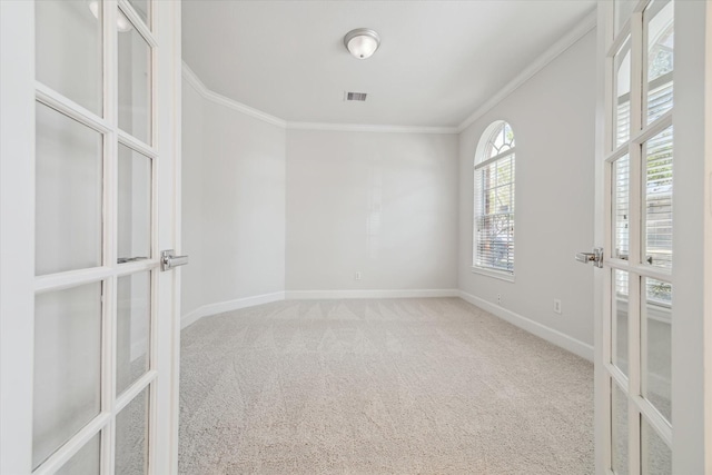 carpeted empty room with visible vents, baseboards, crown molding, and french doors