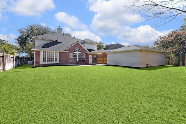 rear view of house featuring brick siding, a lawn, a chimney, and a fenced backyard