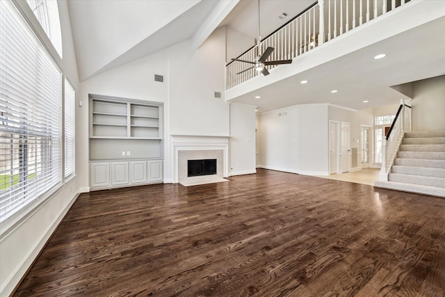 unfurnished living room with stairs, wood finished floors, a fireplace with flush hearth, and baseboards