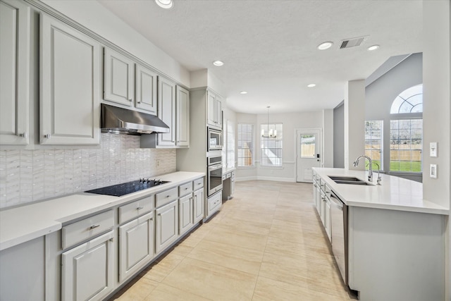 kitchen featuring visible vents, decorative backsplash, appliances with stainless steel finishes, under cabinet range hood, and a sink