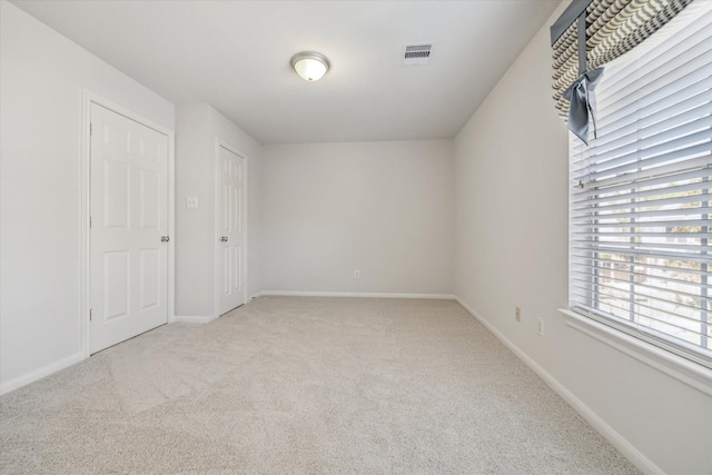 unfurnished bedroom featuring carpet floors, baseboards, and visible vents