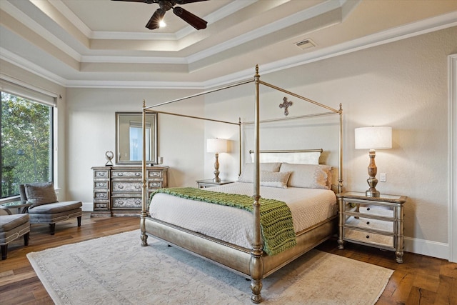 bedroom with ornamental molding, a tray ceiling, visible vents, and hardwood / wood-style floors