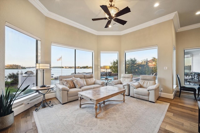 living room with a water view, baseboards, ornamental molding, and wood finished floors