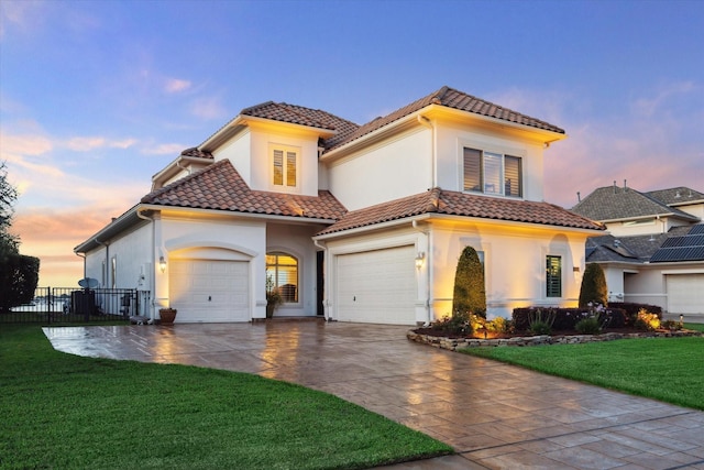 mediterranean / spanish-style house featuring a lawn, fence, a tiled roof, and stucco siding