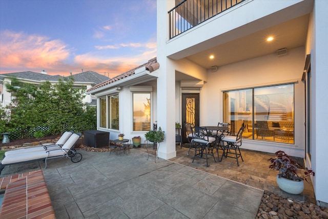 view of patio with a balcony and outdoor dining area