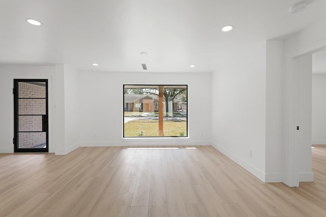 empty room featuring light wood finished floors, a fireplace, baseboards, and recessed lighting