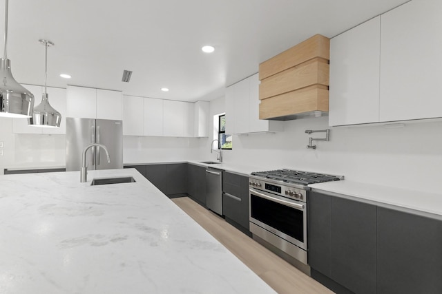 kitchen with appliances with stainless steel finishes, modern cabinets, a sink, and white cabinetry