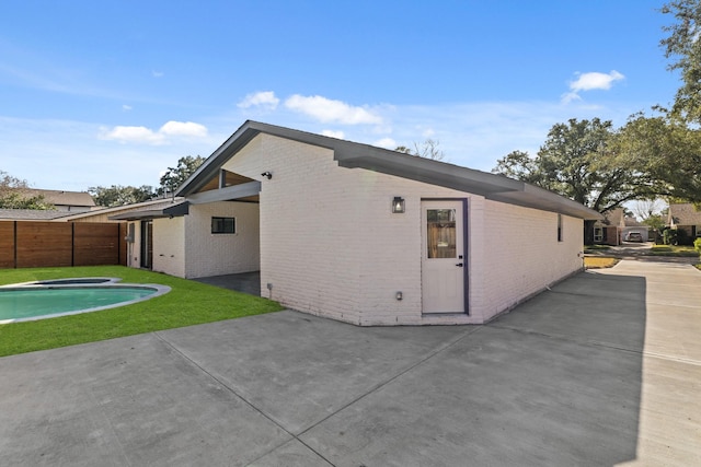 view of property exterior with brick siding and a patio area