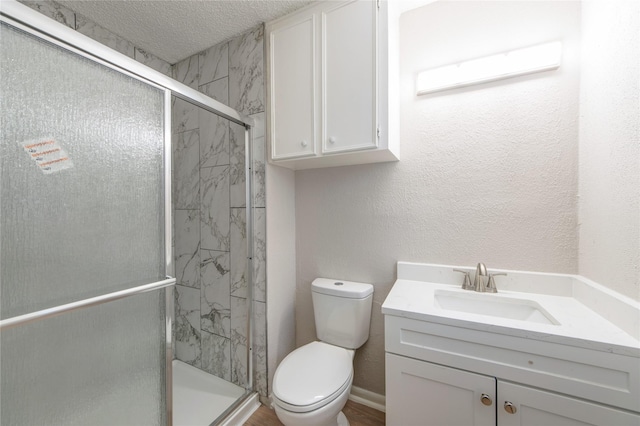 full bathroom featuring a marble finish shower, a textured wall, toilet, a textured ceiling, and vanity