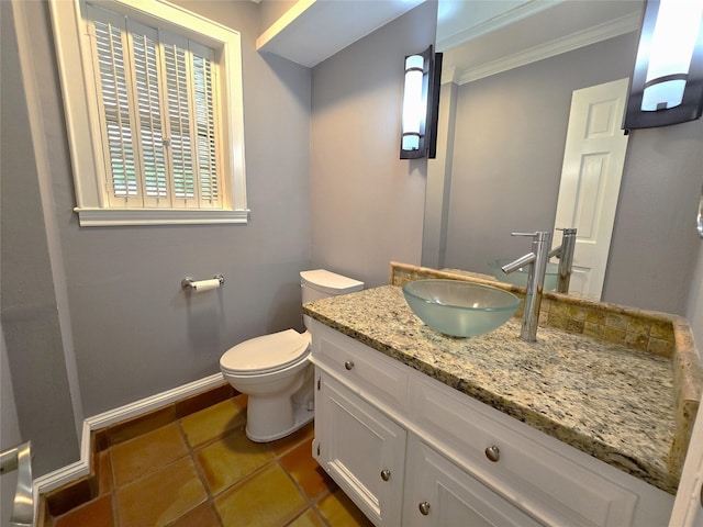 half bathroom with baseboards, toilet, ornamental molding, tile patterned flooring, and vanity