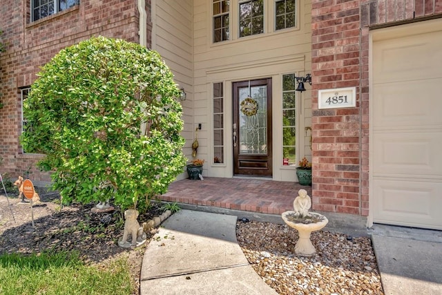 doorway to property featuring a garage and brick siding