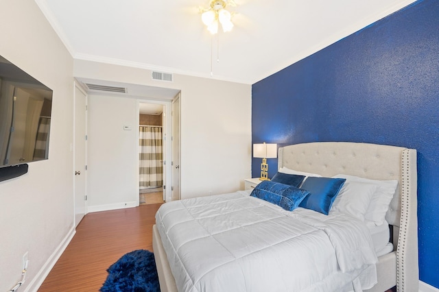 bedroom with ornamental molding, wood finished floors, visible vents, and baseboards