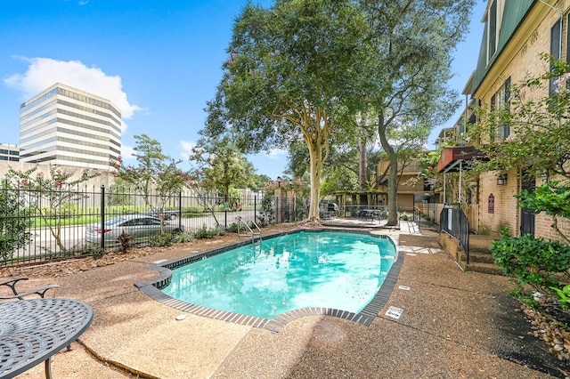 community pool with a patio area and fence