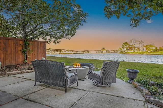 view of patio / terrace featuring an outdoor fire pit, a water view, and fence