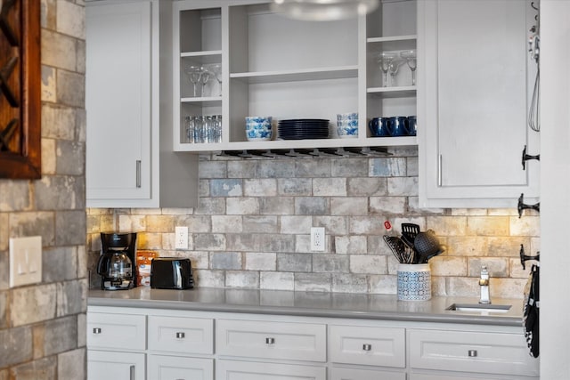 kitchen with a sink, white cabinetry, open shelves, and backsplash